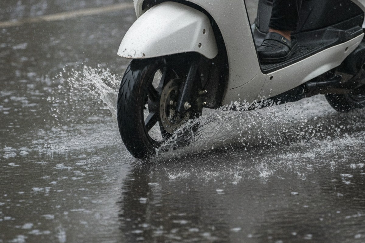 Electric scooter ground clearance above standing water on flooded Indian road during monsoon
