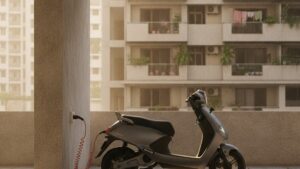 Electric scooter being charged using a standard wall socket in an Indian apartment building parking area